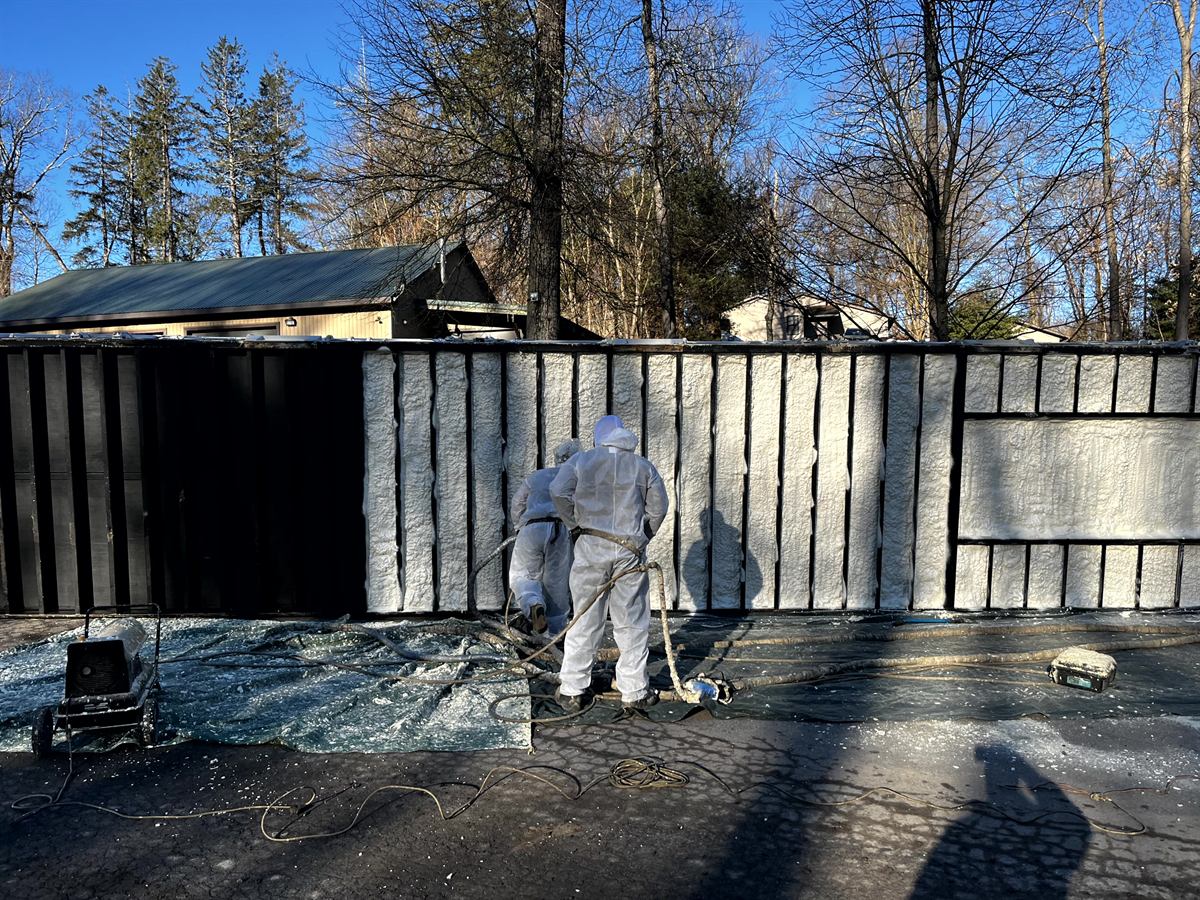 Premium Insulation crew applying spray foam to a foundation exterior